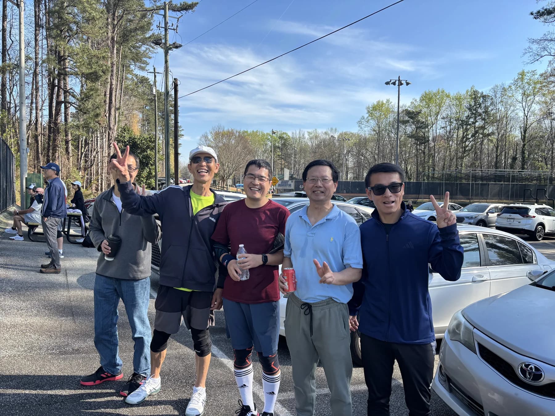 A group of AARSA friends smiling together beside the tennis courts